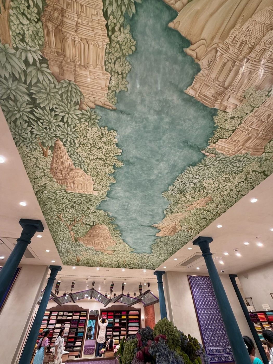 Hand-painted ceiling mural of South Indian temples and rivers above the main saree hall